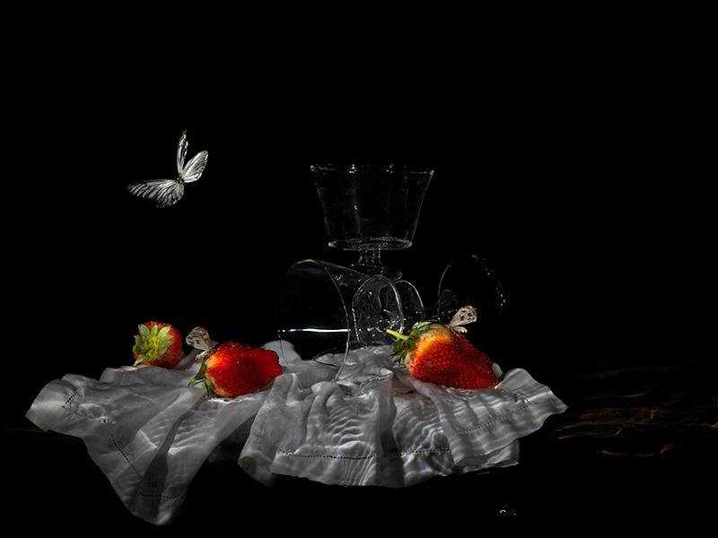 strawberries and wine glass on table with linen cloth and butterfly