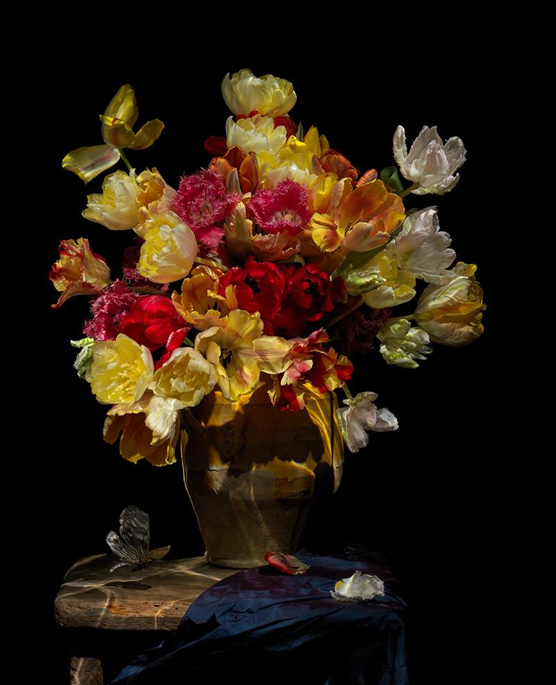 a traditional momento mori still life vanitas of flowers butterflies atop a wooden table laid with silk